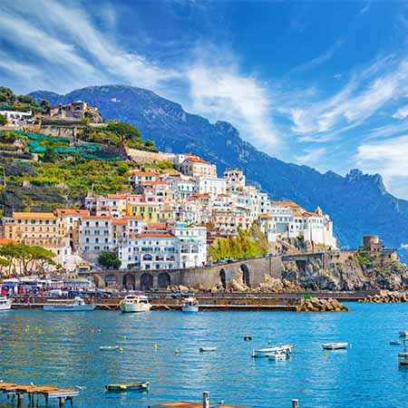 Amalfi Coast wall art featuring colorful cliffside buildings, boats on turquoise water, and dramatic mountain backdrop — Amalfi Coast Wall Art Collection for Mediterranean coastal decor.