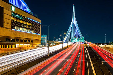 Nighttime view of a cable-stayed bridge in Boston's metropolitan urban area with highway lighting