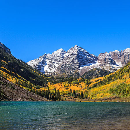 Snow-capped Rocky Mountains near Boulder, Colorado with autumn trees and clear blue lake – scenic nature wall art for rustic home or modern office décor.