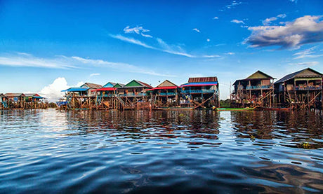 Evening view of a resort town in Cambodia with cloud reflections, log cabin, and village huts.