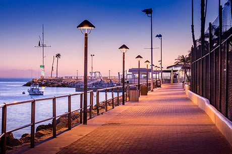 Catalina collection dusk scene featuring ocean view, boardwalk, street lights, and coastal walkway