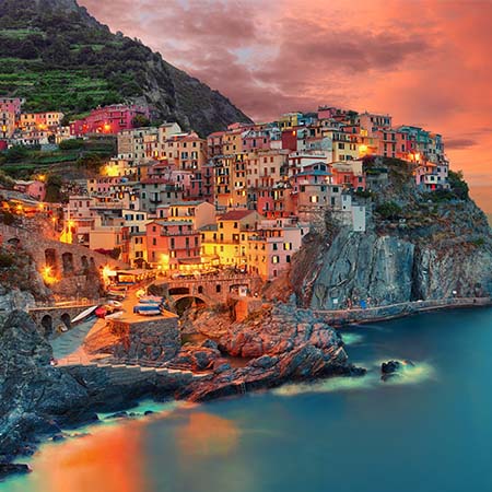 Cinque Terre wall art featuring colorful cliffside village at sunset with glowing lights and dramatic coastal landscape — Cinque Terre Wall Art Collection for Italian seaside decor.