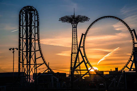 Coney Island Collection wall art featuring a roller coaster amusement ride in the warm sunlight at dusk.