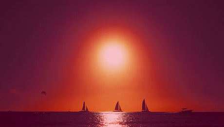 Dominican Republic sunset wall art featuring a sailboat silhouette against a vibrant orange afterglow