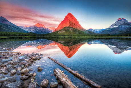 Stunning natural landscape of Glacier National Park featuring blue sky, mountain range, and serene body of water.
