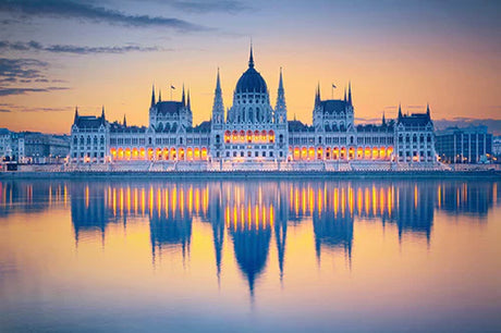 Dusk view of a blue lake reflecting a landmark palace in Hungary at sunset