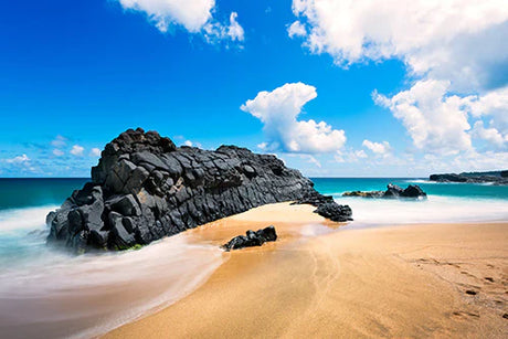 Wall art featuring Kauai's coastal landscape with blue sea, cloudy sky, and rocky beach