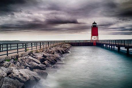 Lake Michigan wall art featuring a lighthouse beacon on a pier with a bridge over the serene ocean.
