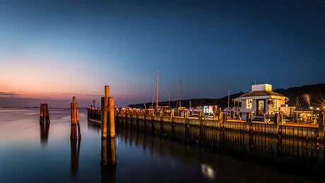 Dusk at Long Island featuring a serene lake view, boat docked at pier, and sky reflections