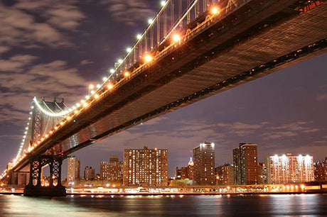 Nighttime view of the Manhattan Bridge, a landmark cable-stayed suspension bridge in a bustling metropolis.
