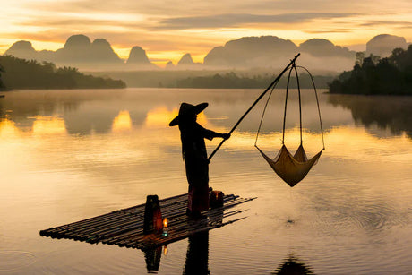 Fisherman on a boat during dusk on a tranquil Thai lake, reflecting leisure and recreation.