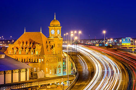 Nighttime cityscape of Virginia featuring lit clock tower, busy highway, and urban landmarks