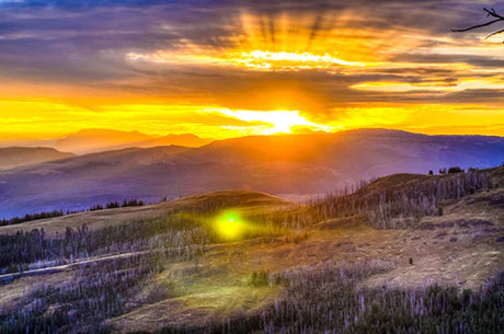 Yellowstone National Park sunrise with vibrant afterglow illuminating mountainous landscape and sky