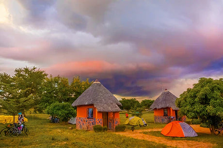 Traditional Zambian village scene with thatched huts, tents and expansive grassland in the Zambia wall art collection.