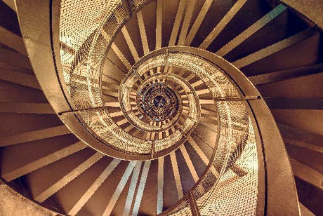 Spiral staircase wall art featuring brown metal handrail and wood stain design in still life photography