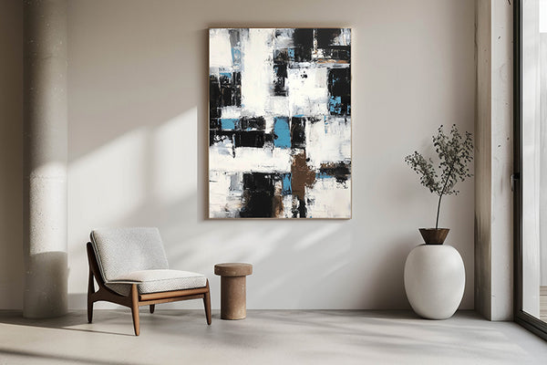 Abstract black, white, and blue wall art displayed in a minimalist modern living room with natural light and neutral decor