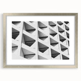 Abstract art print featuring geometric shapes in muted gray and silver tones on a framed canvas.