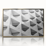 Mid-century modernist art depicting abstract architecture in gold and black tones on a framed acrylic print.