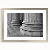 Textured art print featuring abstract columns in muted gray tones on a framed silver mat, suitable for bedroom decor.