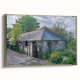 Framed canvas of a vintage landscape painting featuring a derelict building, in muted gold and black tones.
