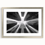 Abstract art print of a skyscraper design in silver frame with mat, in muted gray tones.
