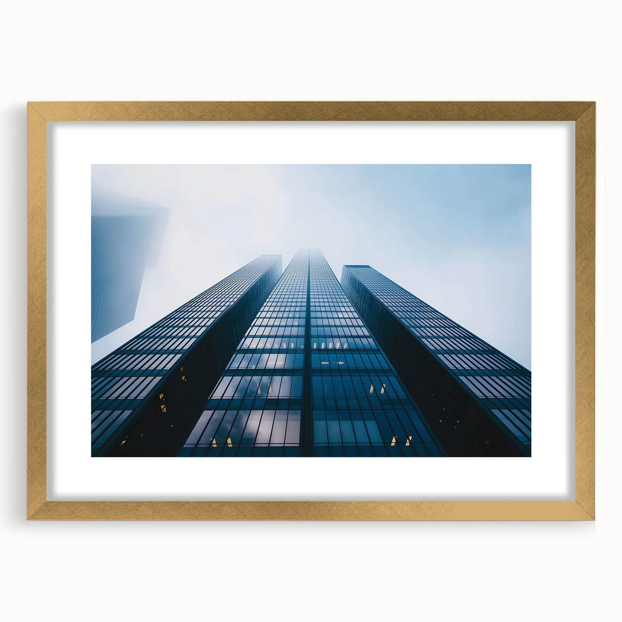 Textured abstract art print of a skyscraper, in muted metallic and gray tones, framed in gold.