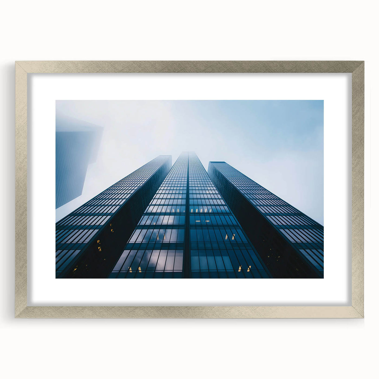 Abstract art print of skyscrapers in muted gray and silver tones on a framed canvas.