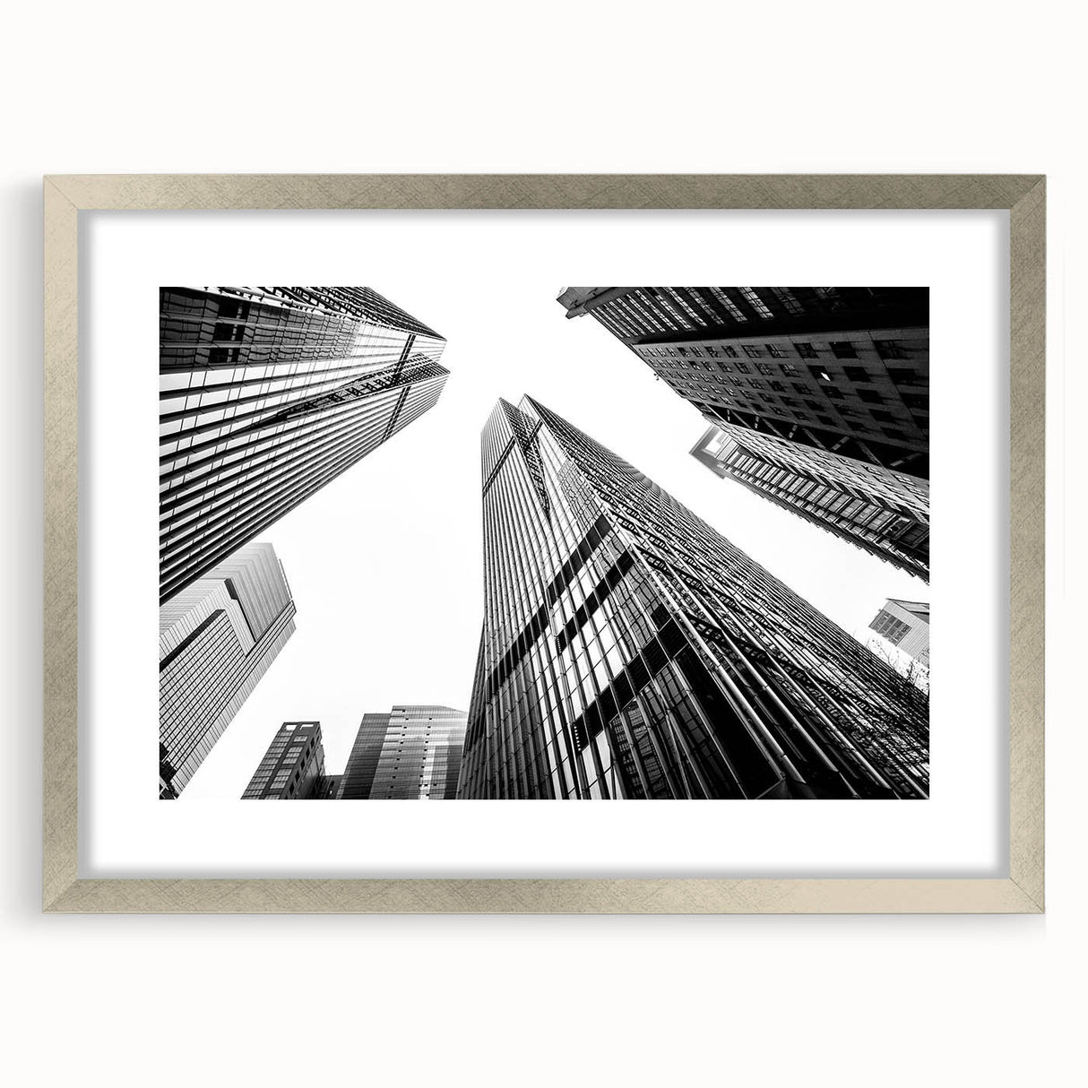 Abstract art print of skyscrapers in muted gray tones on a framed silver mat, suitable for bedroom or dining room decor.
