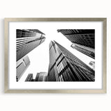Abstract art print of skyscrapers in muted gray tones on a framed silver mat, suitable for bedroom or dining room decor.