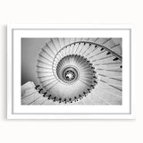Abstract art print of a spiral staircase in monochrome, framed with a white mat.