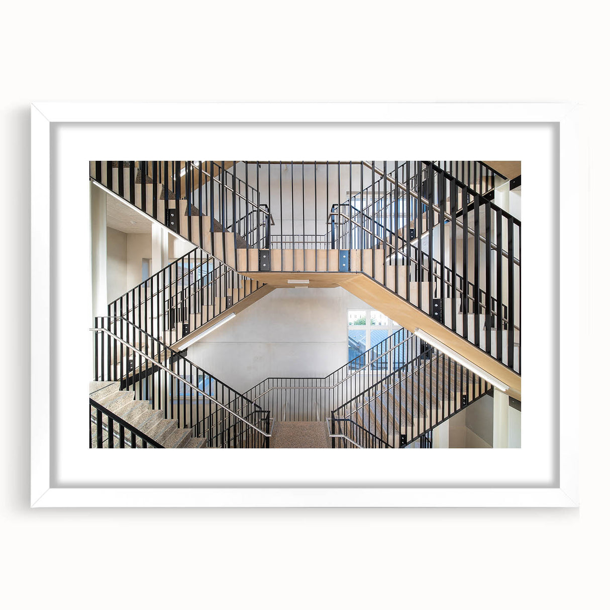 Abstract art print of a spiral staircase in black and white, framed with a white mat.