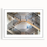 Abstract art print of a spiral staircase in black and white, framed with a white mat.