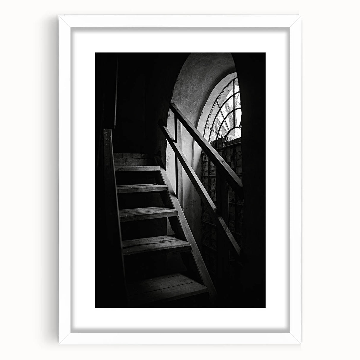 Abstract art print of a spiral staircase in black and white, framed with a white mat.