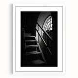 Abstract art print of a spiral staircase in black and white, framed with a white mat.