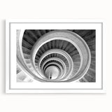 Abstract art print of a spiral staircase in monochrome, framed in white, suitable for bedroom or dining room decor.