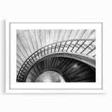 Abstract art print of a spiraling staircase in black and white, framed with a white mat, suitable for dining room decor.