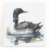 Stretched canvas artwork showcasing a serene loon design, featuring soft blue and gray colors, elegantly leaning against a wall, perfect for nature-inspired decor.