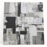 Abstract black and white stretched canvas wall art featuring geometric shapes and fluid lines, leaning against a neutral wall, perfect for modern decor.