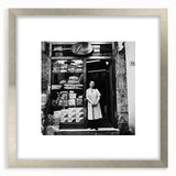 Textured art depicting abstract food and people, in muted earth tones on a framed silver mat, suitable for bedroom decor.