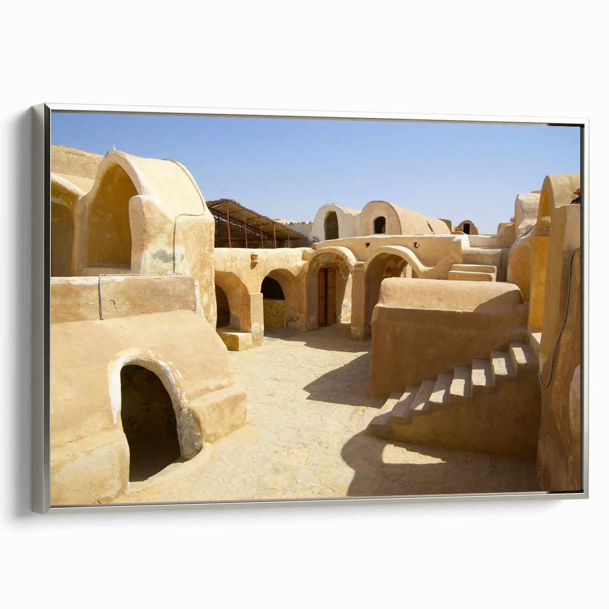 Vintage poster art of a Moroccan scenery in vibrant colors, framed in silver, suitable for living room decor.