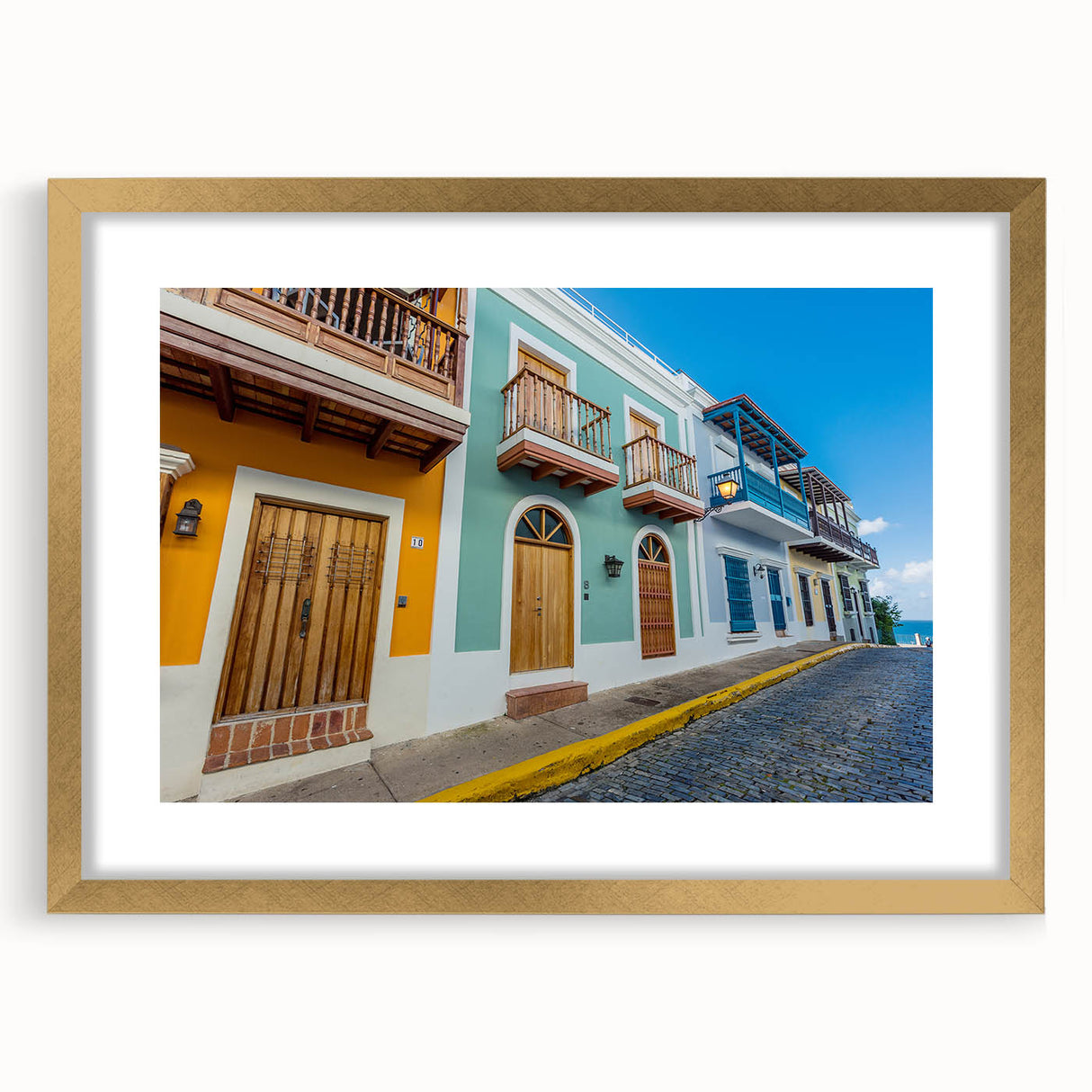 Abstract art print of a Caribbean scenery in muted blue and green tones, framed in gold.