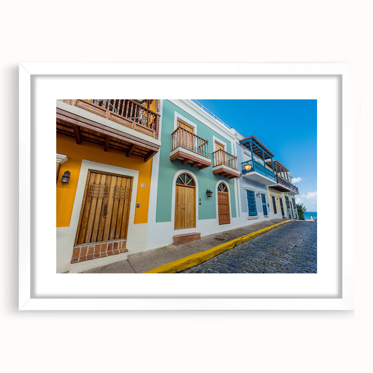 Textured abstract art print depicting Caribbean scenery in muted blue and green tones, framed with a white mat.