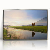 Large art print of a European landscape in muted greens and blues, framed in silver acrylic.