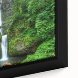 Close-up of a black framed canvas depicting Multnomah Falls in Oregon, featuring vibrant green and blue tones.