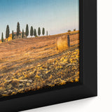 Framed canvas depicting a Tuscan landscape with vibrant green fields and a textured sky, ideal for living room decor.