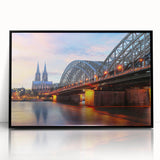 Large abstract wall art depicting a stylized European cityscape in muted gray and black tones, framed in black acrylic.
