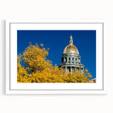 Abstract art print of Denver skyline in muted blue and gray tones on a white framed mat, ideal for dining room decor.
