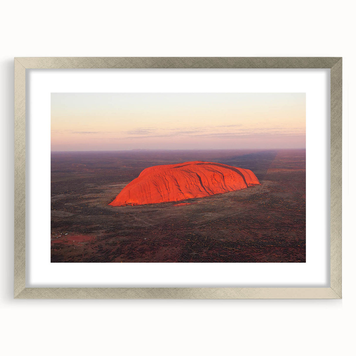 Abstract art print of Ayers Rock in muted orange and brown tones, framed in silver, suitable for dining room decor.