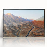 Mid-century modernist art depicting an abstract Iraqi landscape in muted earth tones on a silver-framed acrylic print.