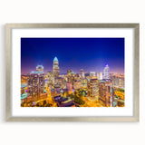 Textured abstract art print of Charlotte skyline in muted blue and gray, framed in silver, suitable for bedroom decor.